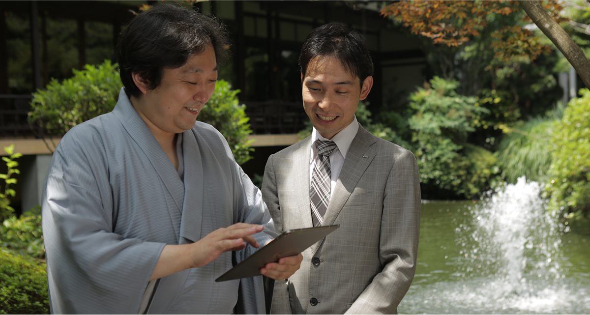 株式会社 陣屋様 ご当主と、ディーアイエスソリューション株式会社 菅野氏が、導入されたシステムを実際にタブレットで操作しているお写真